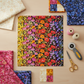 Styled sewing room flat lay with Superbloom Jewel ombré floral quilting cotton by Robin Pickens for Moda Fabrics surrounded by coordinating Superbloom prints and quilting notions – available at IraRobi Quilts