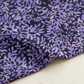 Close-up of Superbloom Leafy Indigo fabric by Robin Pickens for Moda Fabrics, softly draped on a light tabletop with lavender-purple leaves on a dark indigo ground.