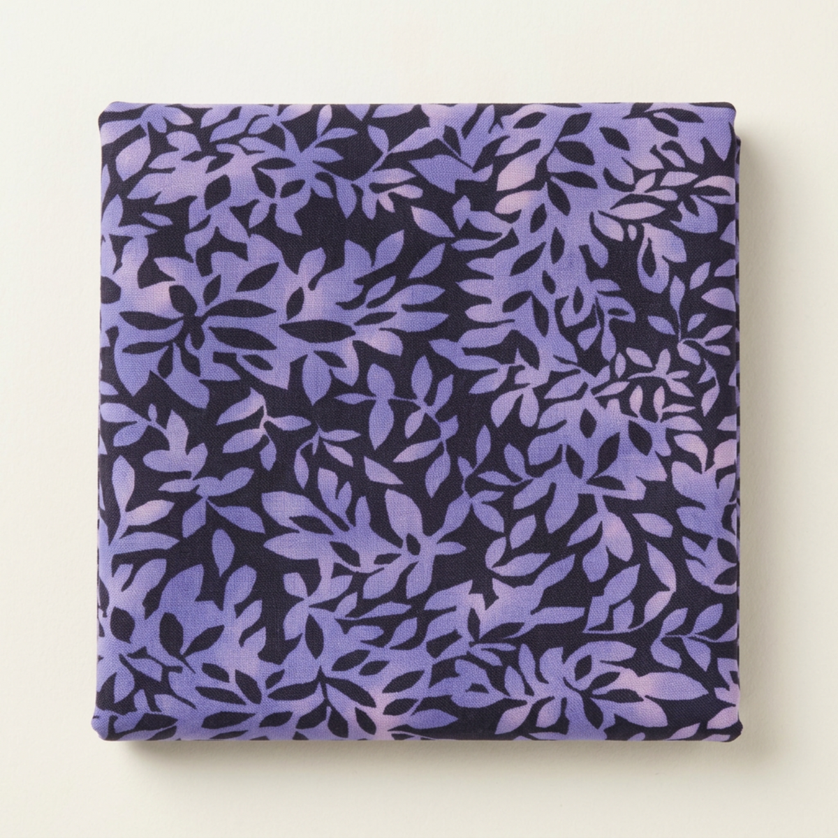 Folded Superbloom Leafy Indigo fabric by Robin Pickens for Moda Fabrics on a light surface, showing lavender-purple leafy branches on dark indigo cotton.