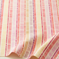 Superbloom Scribble Stripe Cream fabric by Robin Pickens for Moda Fabrics, softly draped in folds along the lower edge, showing coral-red, pink, plum, and golden-yellow stripes on cream cotton.
