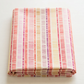 Superbloom Scribble Stripe Cream fabric by Robin Pickens for Moda Fabrics, neatly folded on a light tabletop with colorful vertical scribble-stripe bands on cream cotton.