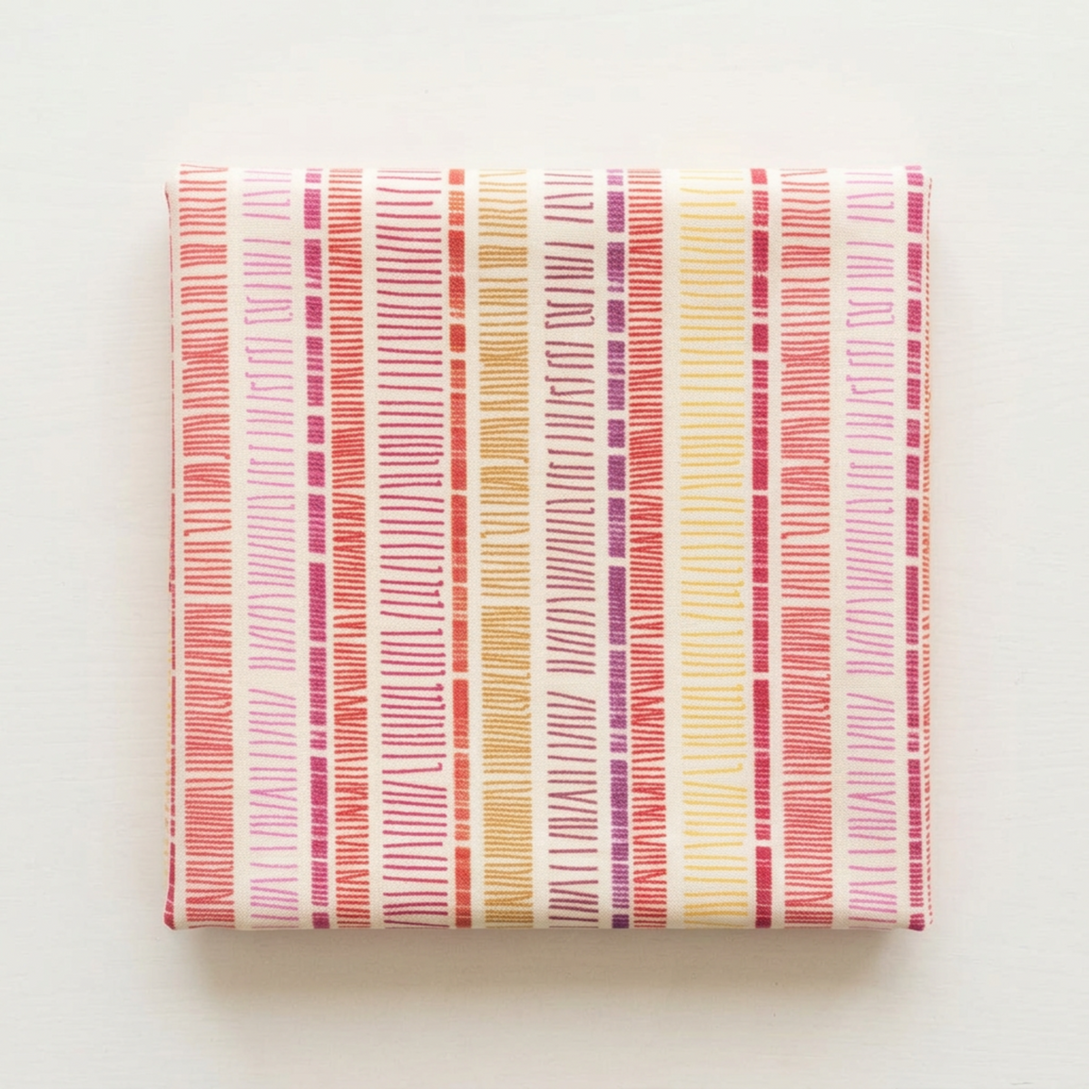 Folded Superbloom Scribble Stripe Cream fabric by Robin Pickens for Moda Fabrics on a light surface, showing colorful hand-drawn stripe bands on cream cotton.