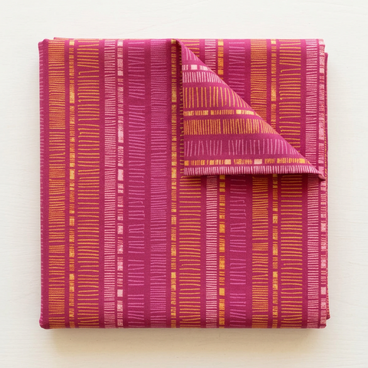 Folded Superbloom Scribble Stripe Orchid fabric by Robin Pickens for Moda Fabrics, with a turned-back corner showing golden-orange and pink stripe bands on orchid-magenta cotton.