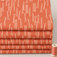 Folded layers of Lazy Afternoon Marmalade fabric on a sewing table, with a ruler and thread beside them.