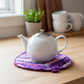Leaf-Shaped Quilted Hot Pad – Violet Jewel under a white teapot | IraRobi Quilts #quiltedhome #hotpad #handmadegift