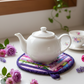 Leaf-Shaped Quilted Hot Pad – Indigo Berry under a white teapot with purple flowers | IraRobi Quilts #quiltedhome #cottagekitchen #handmadegif