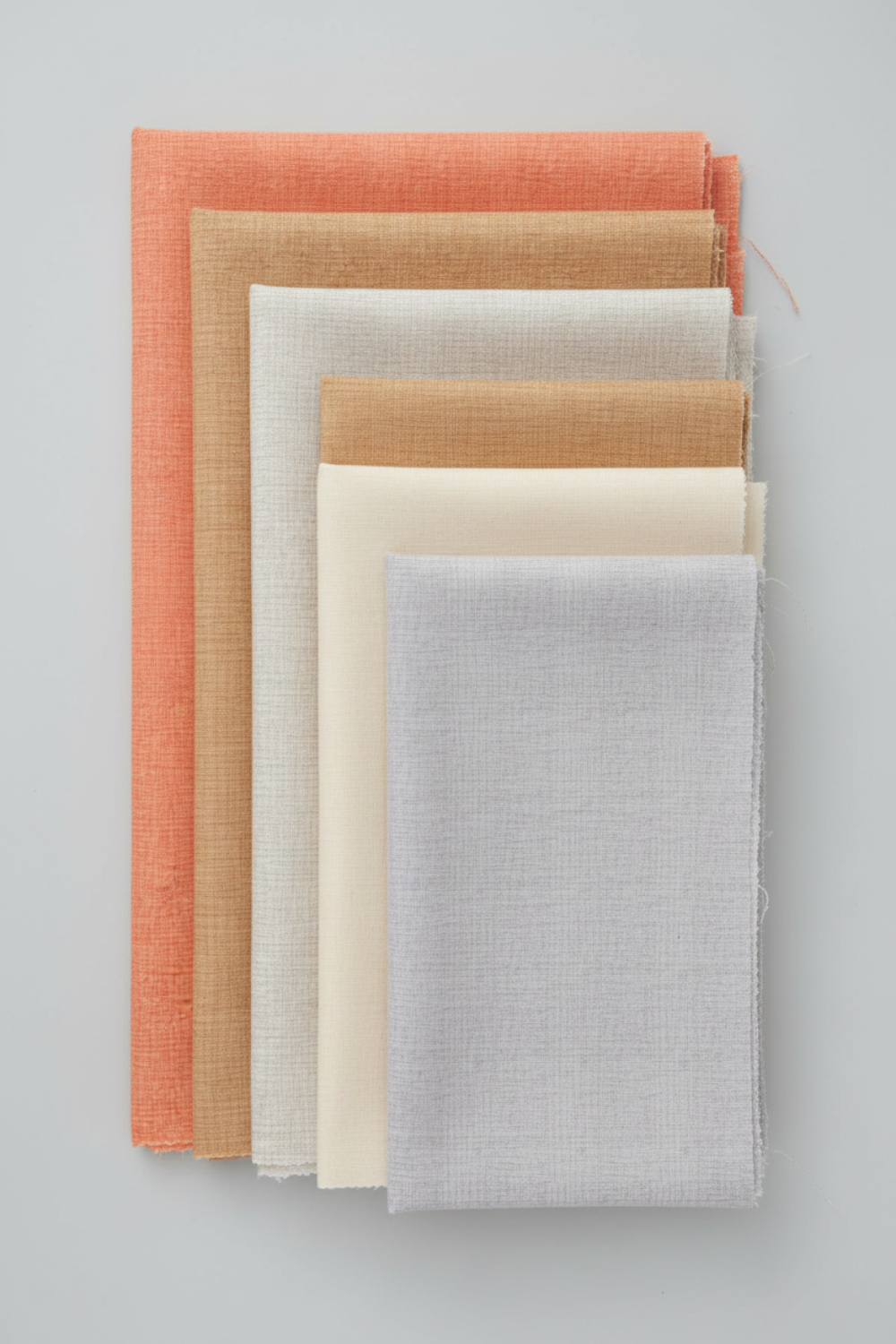 Thatched Basics by Robin Pickens for Moda Fabrics — five coordinating near-solid quilting cottons fanned in coral, shadow, washed linen, cream, and heather colorways, all with subtle crosshatch texture, stacked on light grey background