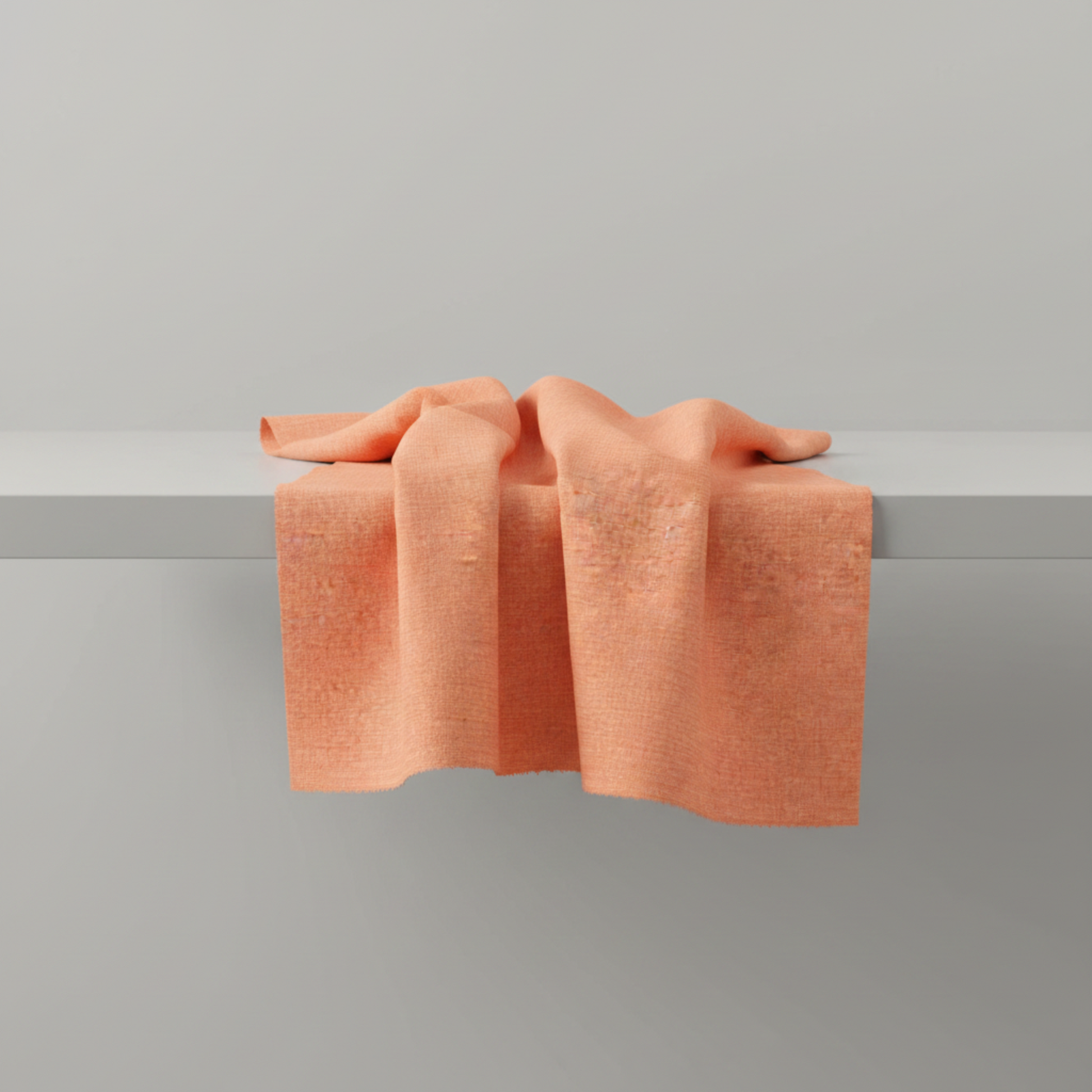 Thatched Coral quilting cotton by Robin Pickens for Moda Fabrics — fabric draped over a grey surface showing natural folds and raw cut edge, warm coral near-solid with subtle crosshatch texture