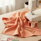 Thatched Coral quilting cotton by Robin Pickens for Moda Fabrics — styled sewing room flat lay with coral fabric alongside vintage sewing machine, coral and cream thread spools, scissors, and cream, dusty rose, and sage fabric swatches