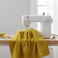 Thatched Green Cury quilting cotton fabric by Robin Pickens for Moda Fabrics draped over a sewing machine in a clean quilting studio with soft natural folds. Coordinating fabrics and quilt patterns are available at IraRobi Quilts.