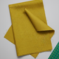 Thatched Green Cury fabric by Robin Pickens for Moda Fabrics styled in a modern quilting studio with a cutting mat and rotary cutter showing the golden olive-curry tonal crosshatch texture. Coordinating fabrics and quilt patterns are available at IraRobi Quilts.