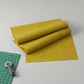 Thatched Green Cury fabric by Robin Pickens for Moda Fabrics partially folded on a cutting mat with a rotary cutter in a clean modern quilting workspace. Coordinating fabrics and quilt patterns are available at IraRobi Quilts.