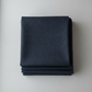 Thatched Soft Black quilting cotton by Robin Pickens for Moda Fabrics — neatly folded in a stack on a light grey background showing the deep navy-black ground with signature crosshatch texture. 100% cotton, 44–45" wide. Available at IraRobi Quilts.