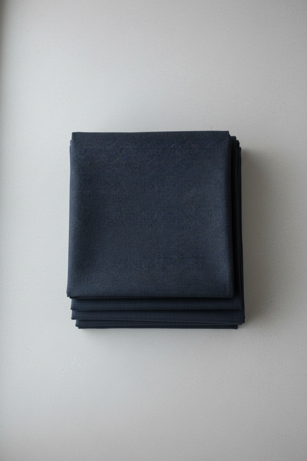Thatched Soft Black quilting cotton by Robin Pickens for Moda Fabrics — neatly folded in a stack on a light grey background showing the deep navy-black ground with signature crosshatch texture. 100% cotton, 44–45" wide. Available at IraRobi Quilts.