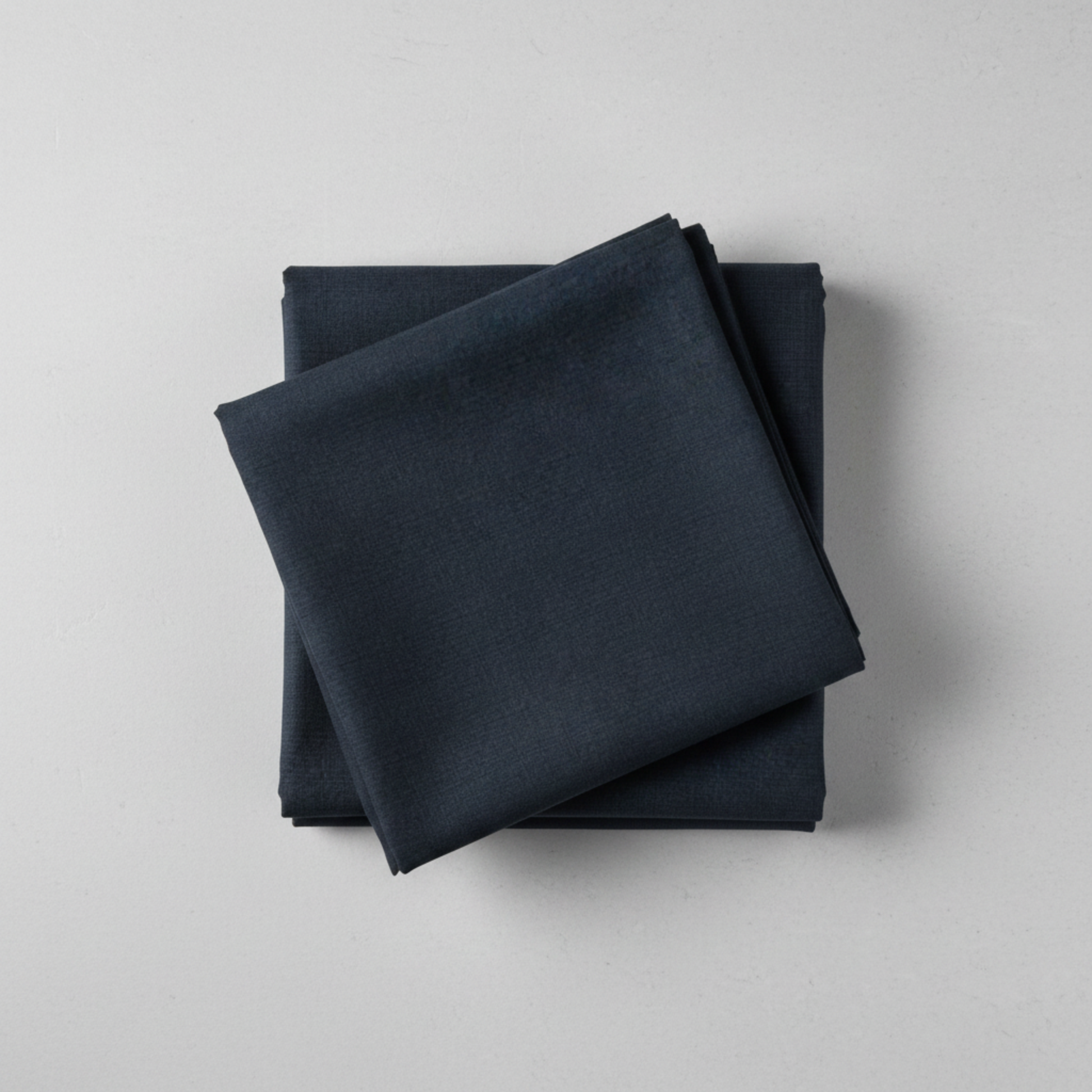 Thatched Soft Black quilting cotton by Robin Pickens for Moda Fabrics — neatly folded in a stack on a light grey background showing the deep navy-black ground with signature crosshatch texture. 100% cotton, 44–45" wide. Available at IraRobi Quilts.