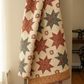 Traditional folk-art quilt featuring The Fox Homestead fabrics by Stacy West for Henry Glass — slate green tumbling cubes, cream daisy clusters, rust leaves and berries, and sand paisley swirl quilting cottons
