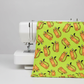 Safari Fun Tiger Too Lime by Terry Runyan for Benartex — fabric draped over a white sewing machine showing drape and hand of the lime green quilting cotton with tossed illustrated tigers