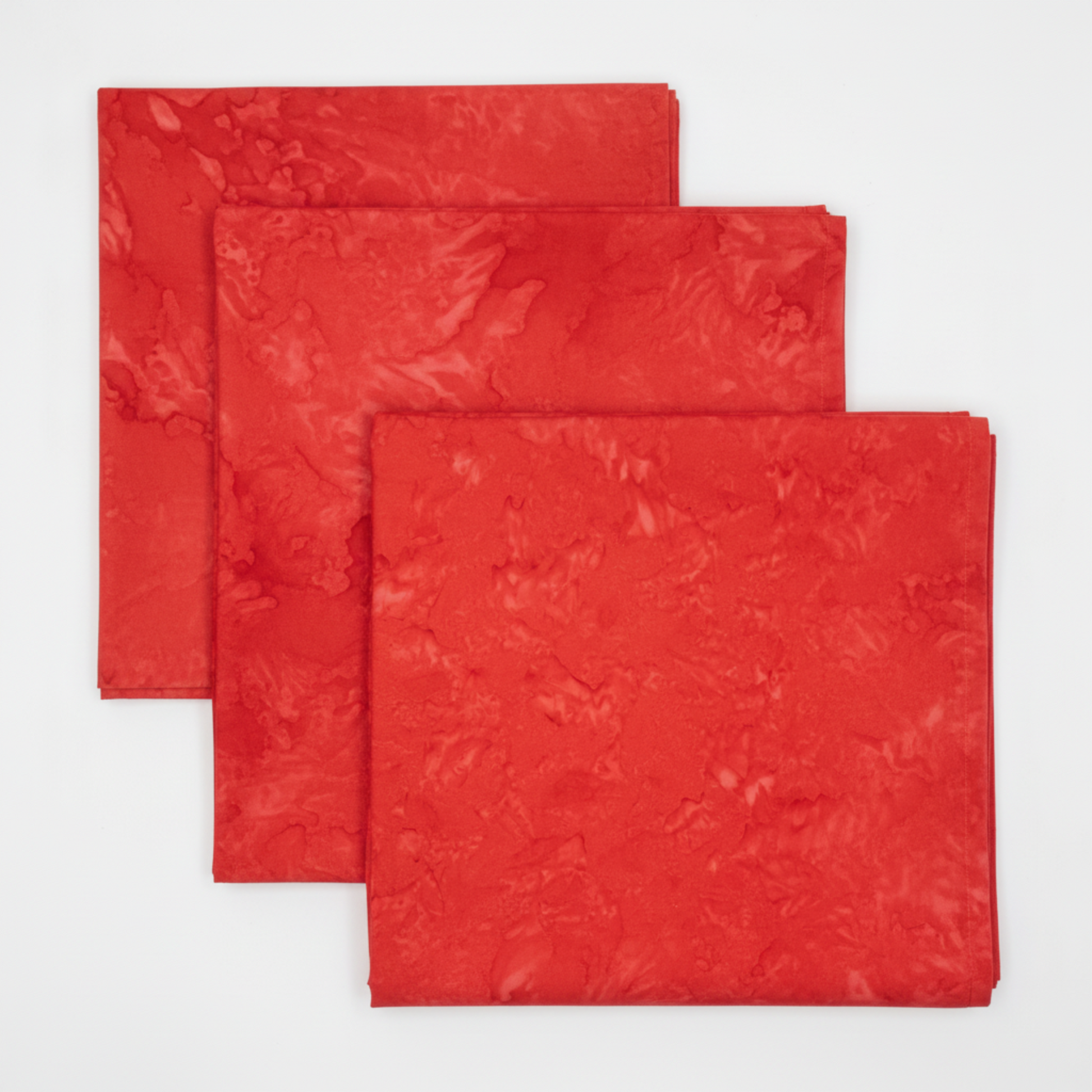 Expressions Batiks Hand-Dyes Tomato Red quilting cotton fabric by Riley Blake Designs in three neatly folded squares stacked on a white surface showing bold vivid tomato red tonal hand-dyed batik with subtle lighter rose highlights and deeper crimson organic mottled variation – 100% cotton batik, 43–44" wide