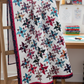 Triangles Galore quilt pattern DTTP102 by Sarah Furrer for Studio 180 Design — scrappy spinning triangle blocks in multicolor batiks on white background with raspberry and navy borders — fat quarter friendly in crib, lap, twin, and full sizes — uses Tucker Trimmer III tool — Studio180Design.net