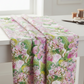 Decoupage Pink Lilac floral quilting fabric draped over a white sewing table, showing its pink, lilac, and green botanical print.