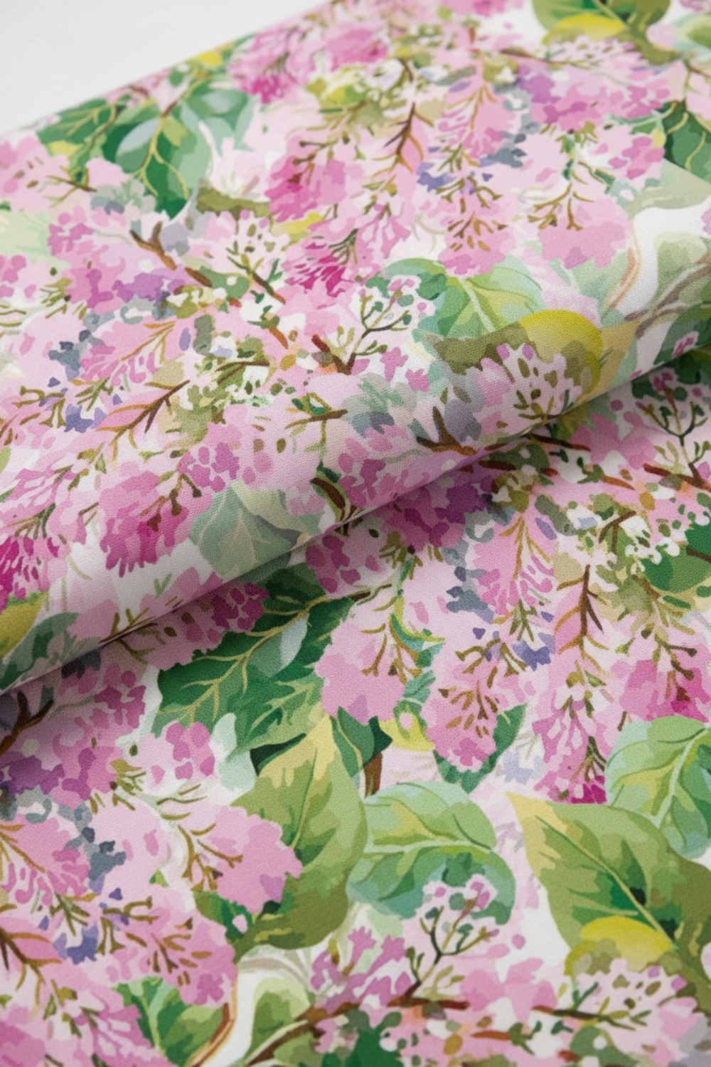 Close-up of Decoupage Pink Lilac quilting fabric draped in a soft fold, showing its layered floral pattern and textile texture.