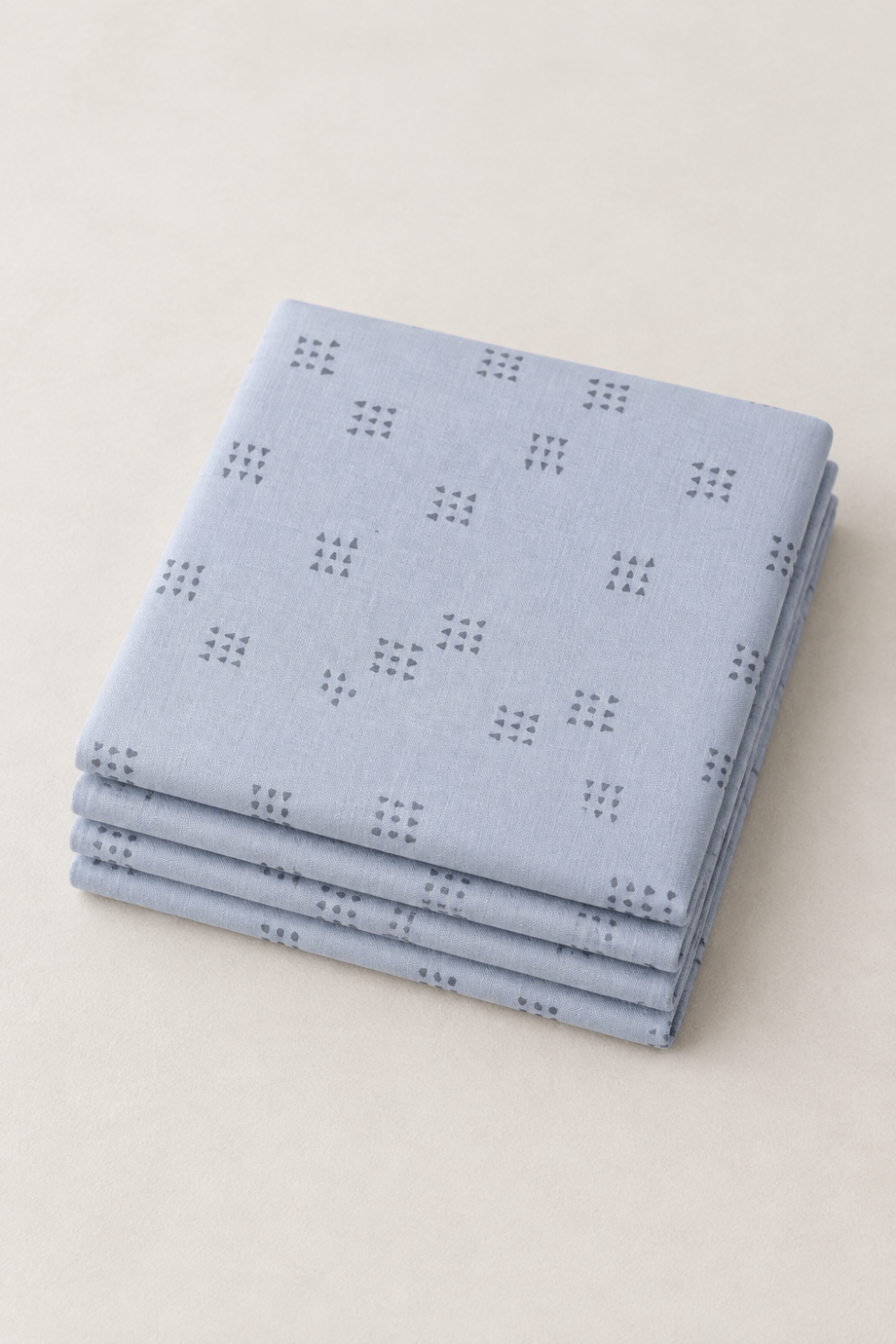 Folded stack of Celestial Nine Triangle Stardust fabric by Zen Chic for Moda Fabrics, with charcoal triangle clusters on pale blue-gray.