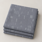 Folded stack of Celestial Strokes Aluminum fabric by Zen Chic for Moda Fabrics, featuring fine white marks on aluminum gray.
