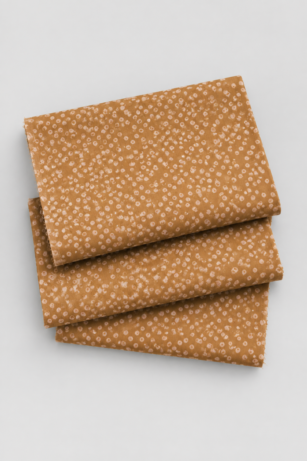 Lazy Afternoon Bronze fabric folded in three layers on a light background, showing its scattered pale dotted print.