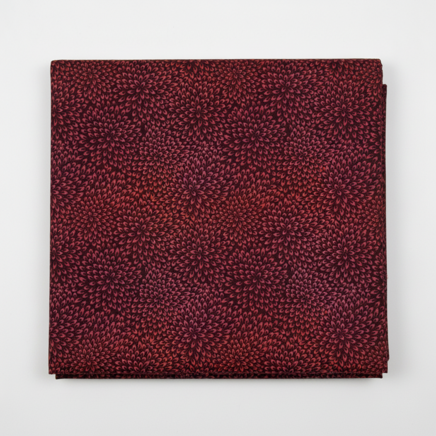 Vivid Mums Spice Red quilting cotton fabric folded to show dense allover chrysanthemum burst blender with hundreds of tiny pointed petals radiating in spiraling formations in deep crimson, rich red, coral-orange, gold, and purple-mauve on dark near-black burgundy by Jason Yenter for In The Beginning Fabrics, 100% cotton, 3 yard cut