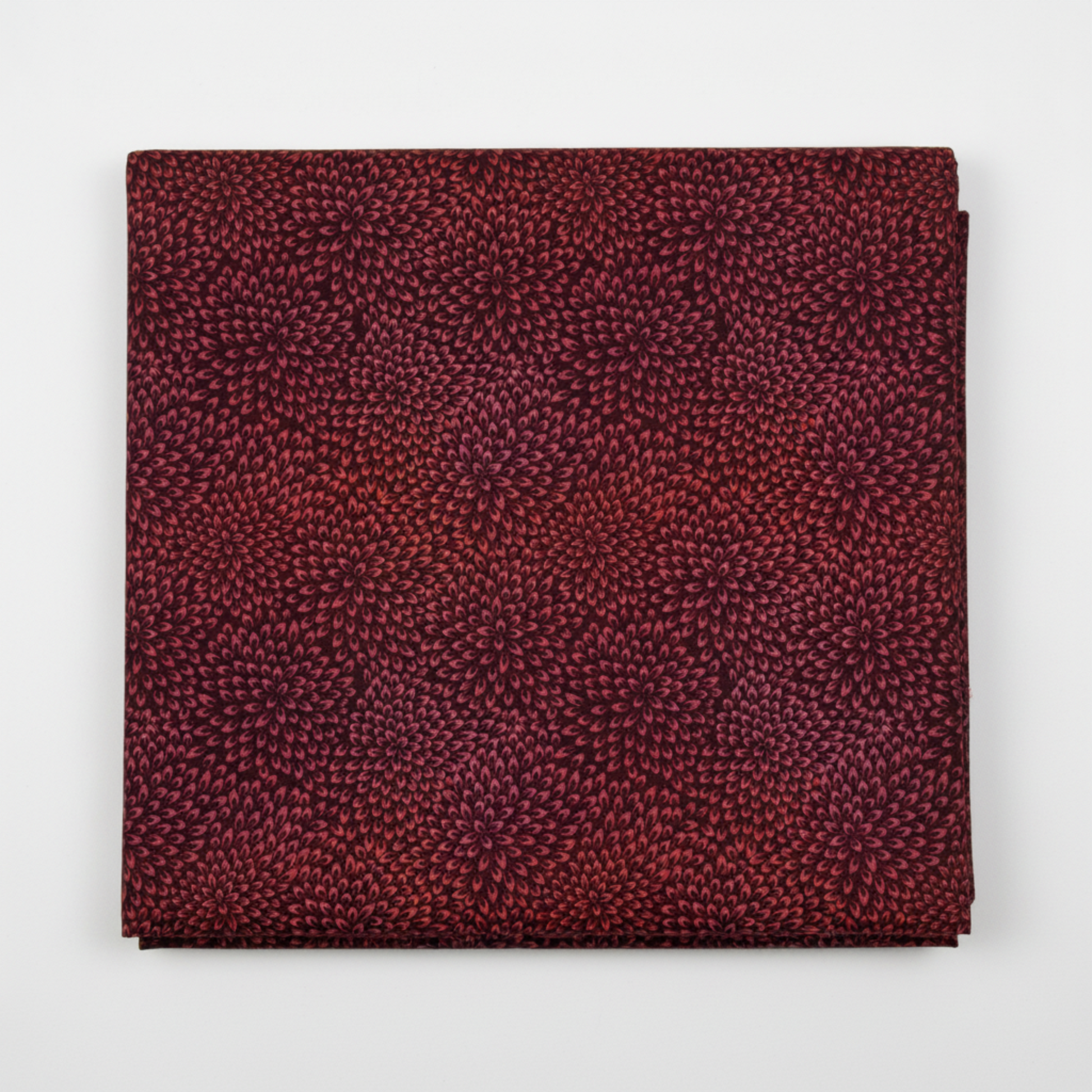 Vivid Mums Spice Red quilting cotton fabric folded to show dense allover chrysanthemum burst blender with hundreds of tiny pointed petals radiating in spiraling formations in deep crimson, rich red, coral-orange, gold, and purple-mauve on dark near-black burgundy by Jason Yenter for In The Beginning Fabrics, 100% cotton, 3 yard cut