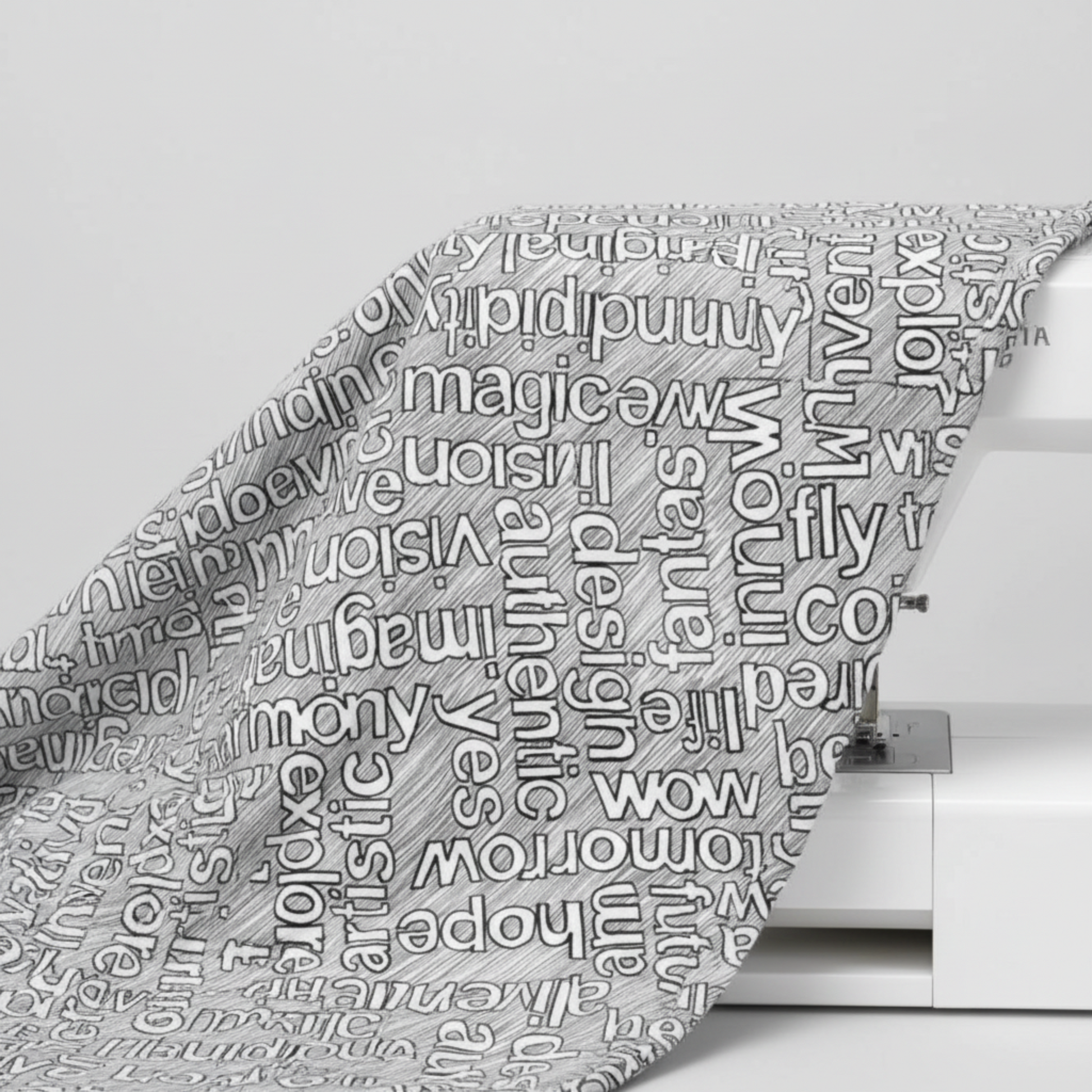 Writing on the Wall Well Worded White quilting cotton draped over sewing machine edge — grey typography fabric by FreeSpirit Fabrics
