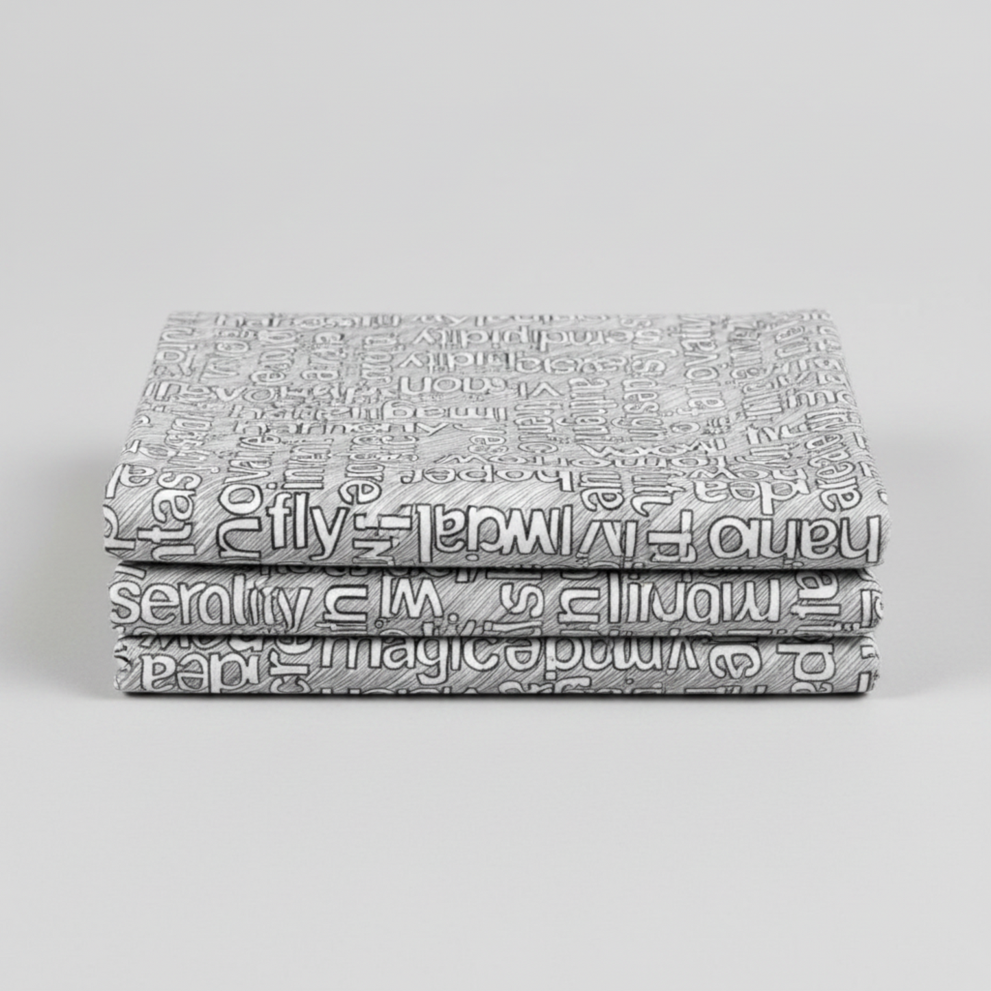 Writing on the Wall Well Worded White quilting cotton in soft fold stack — grey background with white and black word art typography, FreeSpirit Fabrics