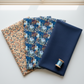 Whimsy Anemones and Berry Pods Blue 3 Yard Cut quilting cotton by Jason Yenter for In The Beginning Fabrics — shown in a coordinate fan with complementary Whimsy collection fabrics in navy and cream botanical prints. Coordinating fabrics and quilt patterns are available at IraRobi Quilts.
