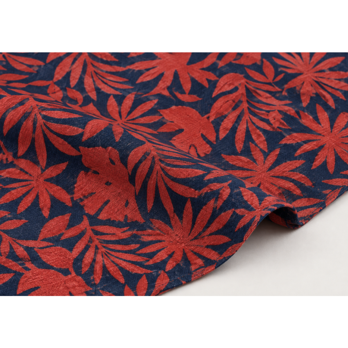 Close-up of Breezeway Red/Blue Textured Palms fabric draped to show its red tropical foliage print, deep blue ground, and woven cotton texture.