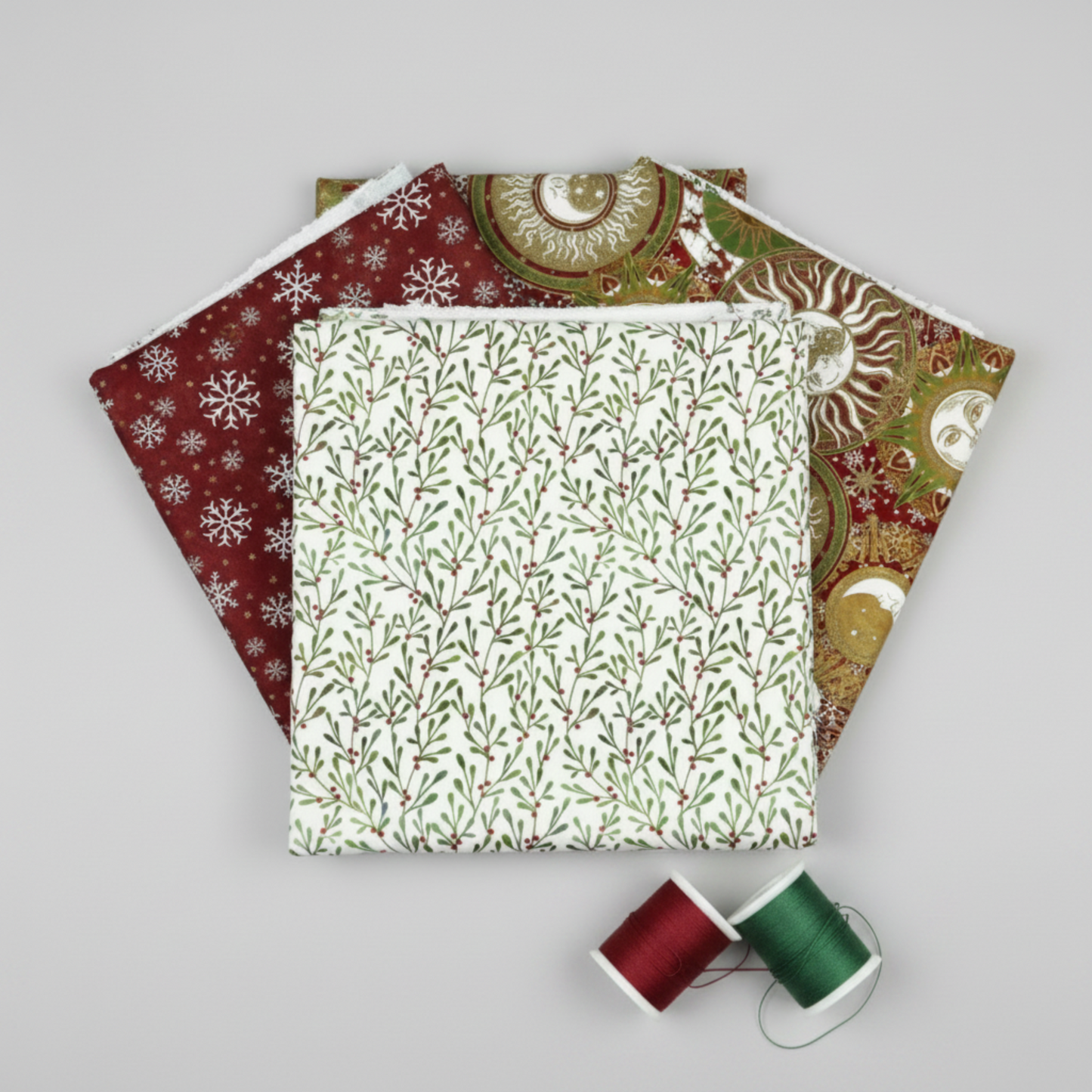Winter Solstice II White Branches quilting cotton by Jason Yenter for In The Beginning Fabrics shown in a coordination stack with Red Snowflakes Metallic and Multi Celestial Metallic from the Winter Solstice II collection, with coordinating red, green, and cream thread bobbins. Quilt blocks shown for inspiration. Coordinating fabrics and quilt patterns are available at IraRobi Quilts.