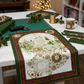 Winter Solstice II Metallic Quilt Panel 36" by Jason Yenter for In The Beginning Fabrics — panel laid flat on a cutting table work in progress in a cozy holiday sewing room with fairy lights, coordinating green and burgundy fabric strips, rotary cutter, gold metallic thread spools, holly sprigs, and a mug of tea. Coordinating fabrics and quilt patterns are available at IraRobi Quilts.