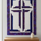 The Wondrous Cross purple, blue, and white wall quilt hanging above an oak console with a cream vase beside a window.