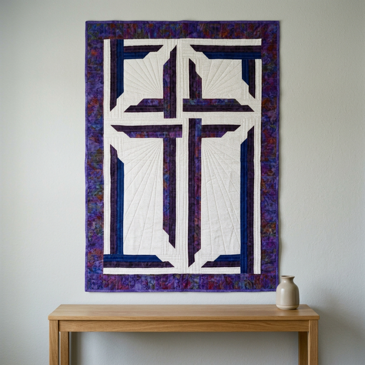 The Wondrous Cross purple, blue, and white wall quilt displayed above an oak console with a cream ceramic vase.