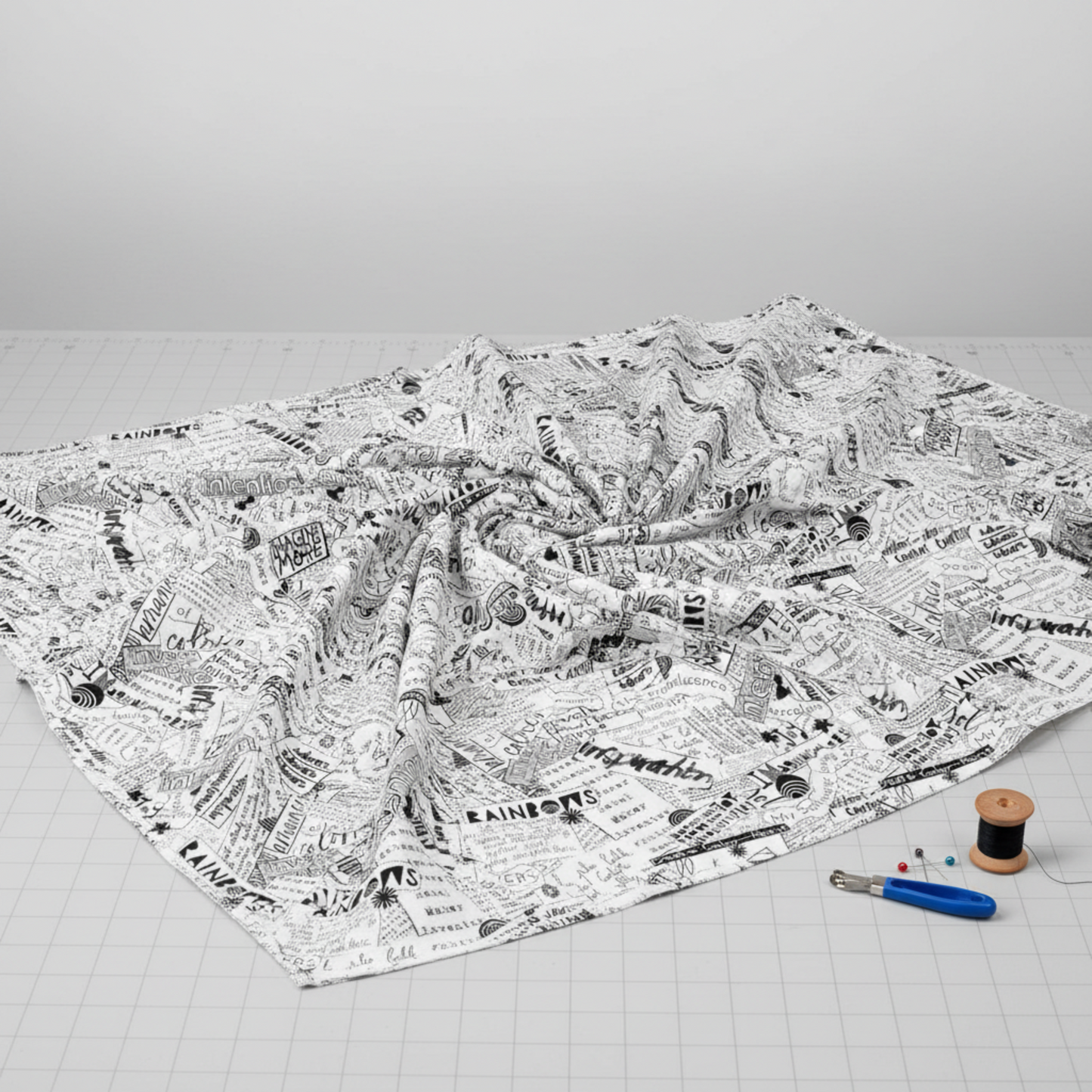 Writing on the Wall Word Collage White quilting cotton fanned flat in quilting workspace with notions — black and white word collage fabric by FreeSpirit Fabrics