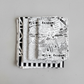 Writing on the Wall Word Collage White quilting cotton by FreeSpirit Fabrics — coordination stack of four modern black and white fabrics fanned on light grey background, including bold word collage, geometric, dot, and stripe prints