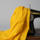 Yellow quilting cotton with orange polka dots draped over a vintage black Singer sewing machine on light grey background — IraRobi Quilts